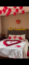 Decoración romántica de habitación con globos rojos, pétalos de rosa en forma de corazón y letras Feliz Cumpleaños