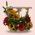 Arreglo floral con girasoles y gerberas en ventana de madera artesanal
